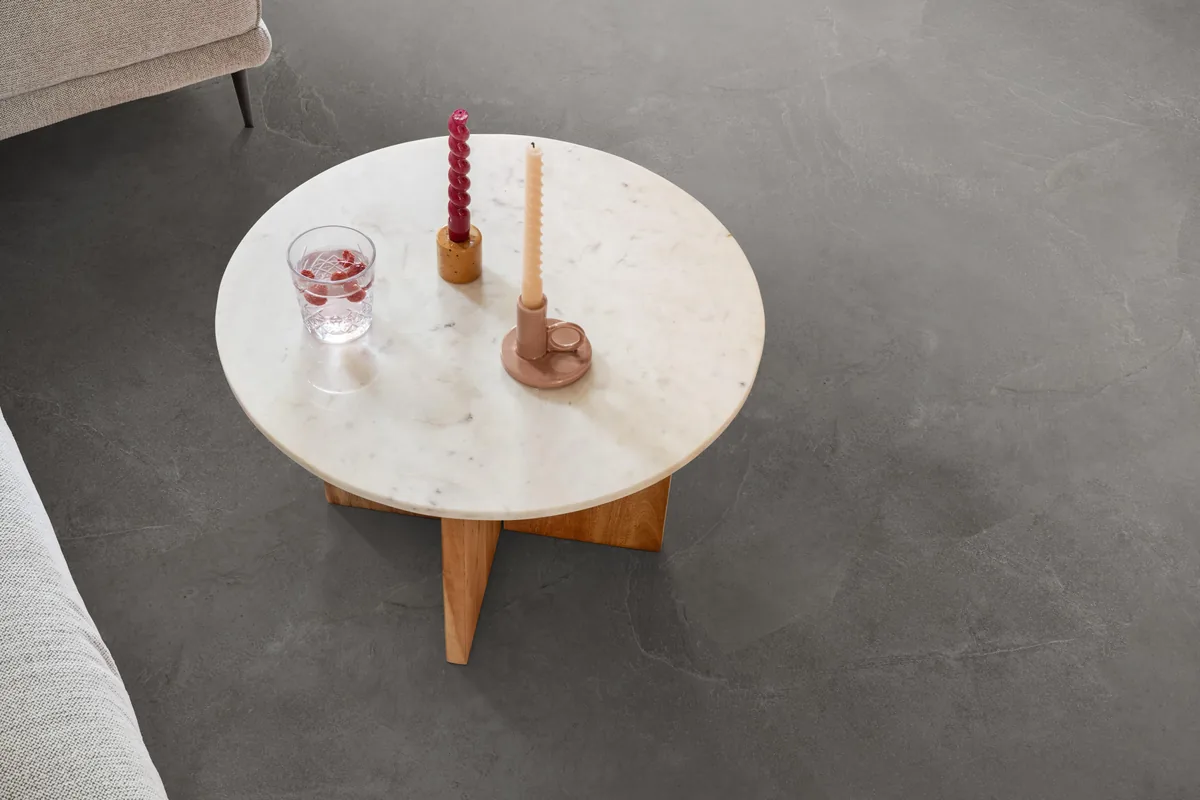 Stanmore / Noveno dark grey, plak pvc in een woonkamer, met een ronde marmeren salontafel en twee kaarsen