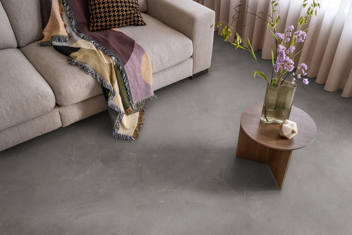 Stanmore / Noveno dark grey, plak pvc in een woonkamer, met een beige bank en een ronde bijzettafel met bloemen