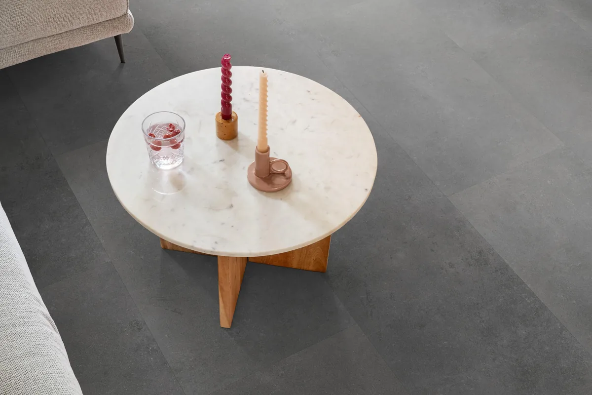 Southwark / Sarino dark grey, plak pvc in een woonkamer, met een ronde marmeren salontafel en twee kaarsen