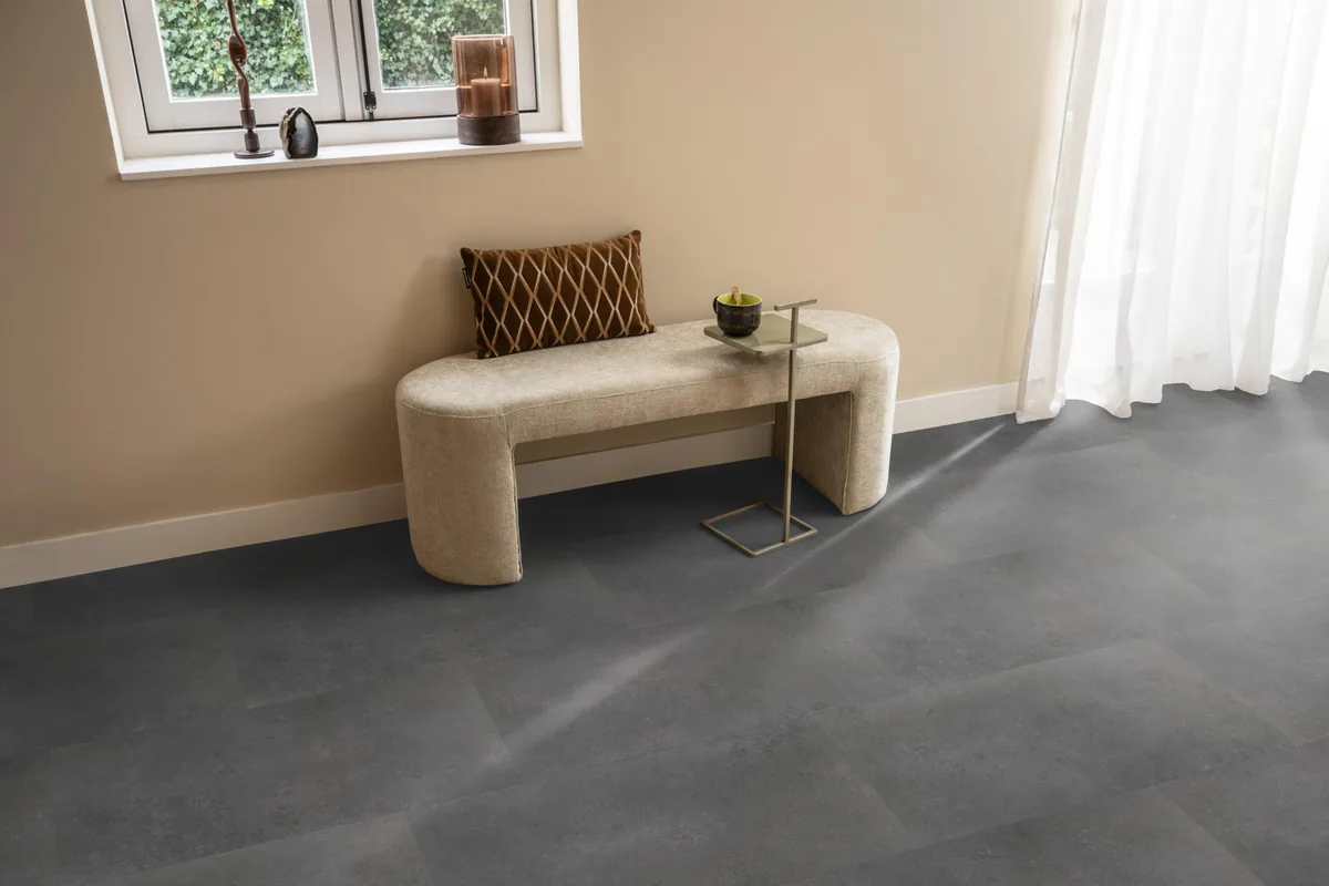 Southwark / Sarino dark grey, plak pvc in een hal, met een bankje onder het raam en zonlicht over de vloer