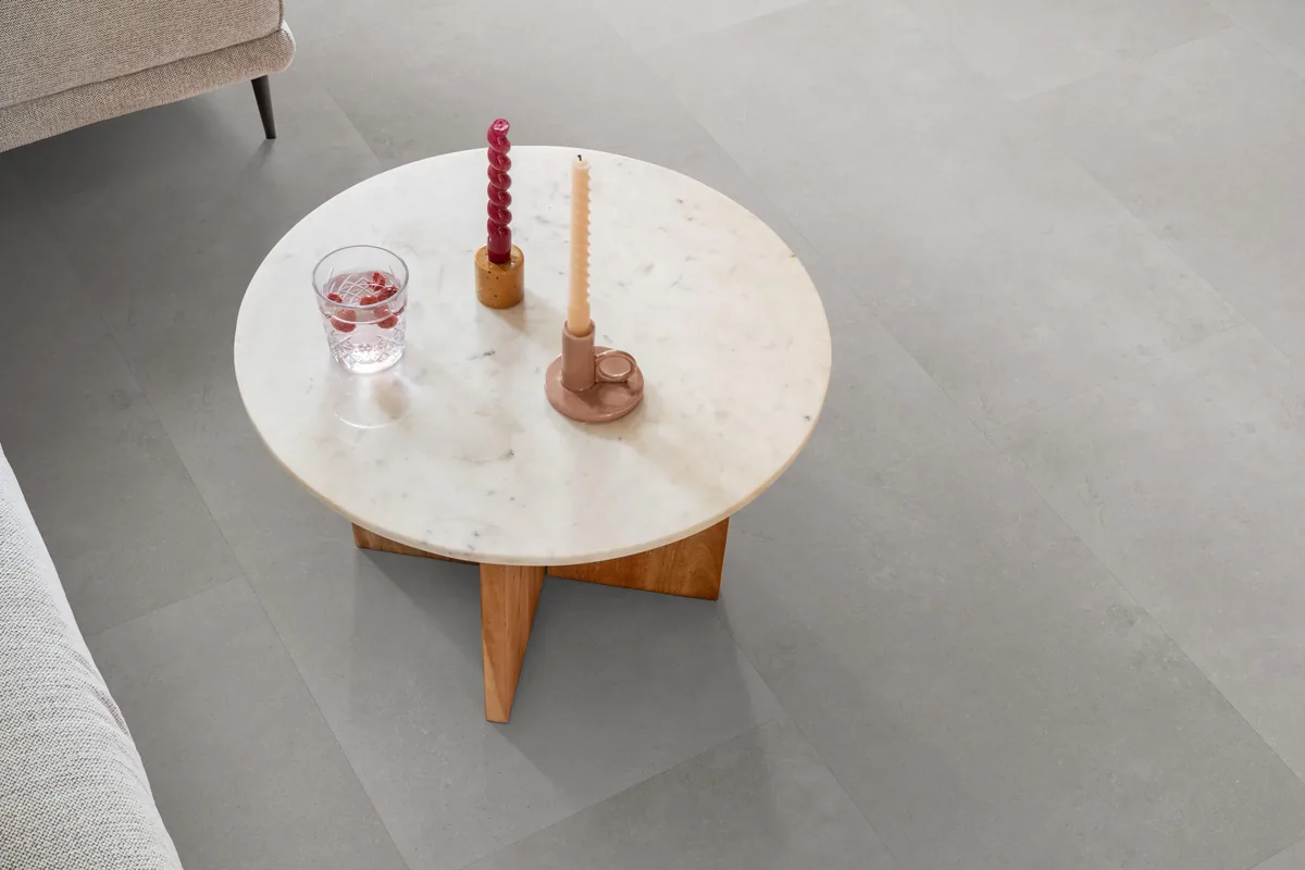 Southwark / Sarino grey, plak pvc in een woonkamer, met een ronde marmeren salontafel en twee kaarsen