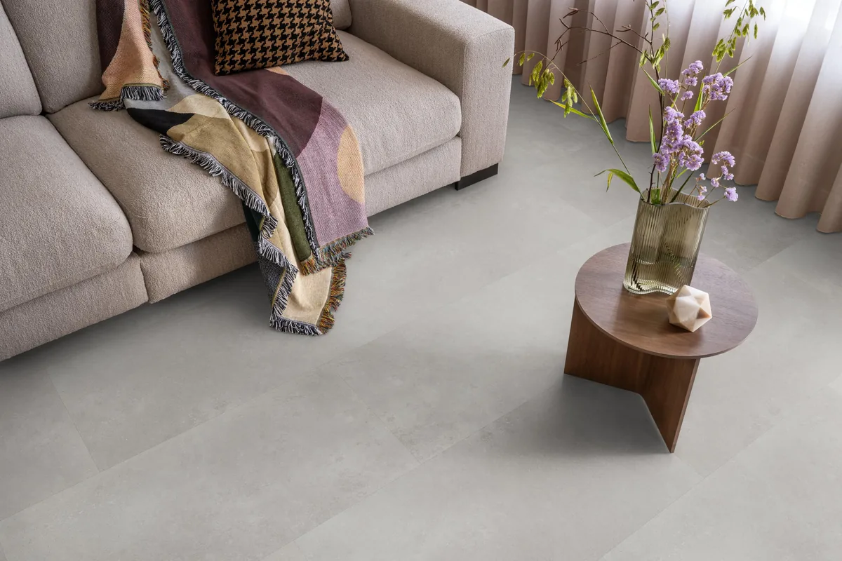 Southwark / Sarino grey, plak pvc in een woonkamer, met een beige bank en een ronde bijzettafel met bloemen