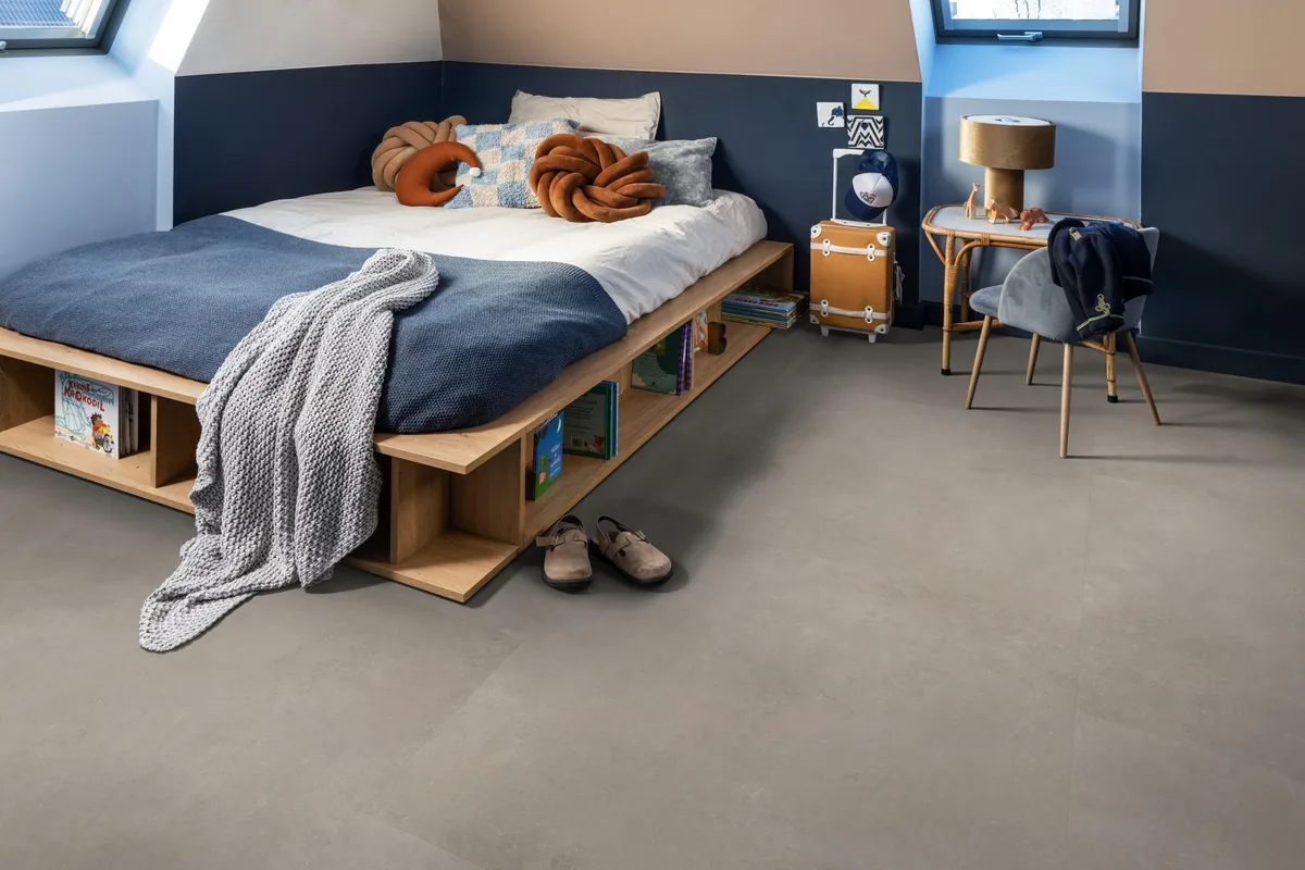 Southwark / Sarino light grey, plak pvc in een slaapkamer onder een schuin dak, met een houten bedombouw en sloffen ervoor