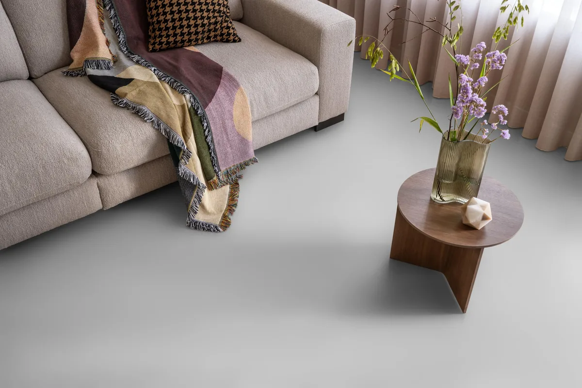 Southwark / Sarino light grey, plak pvc in een woonkamer, met een beige bank en een ronde bijzettafel met bloemen