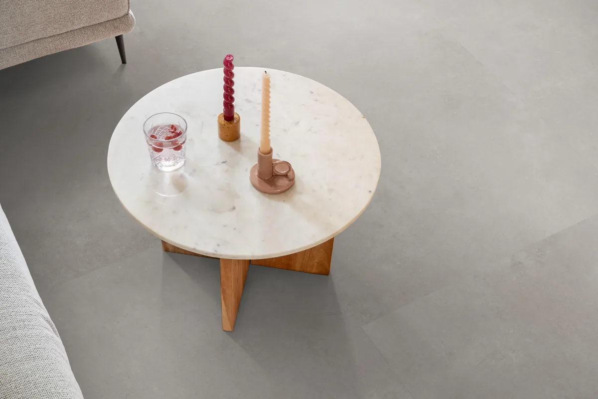 Southwark / Sarino grey, plak pvc in een woonkamer, met een ronde marmeren salontafel en twee kaarsen