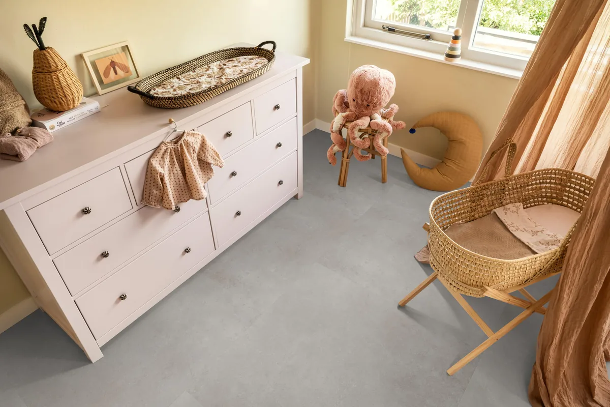 Southwark / Sarino grey, plak pvc in een babykamer, met een witte commode en een rieten wieg