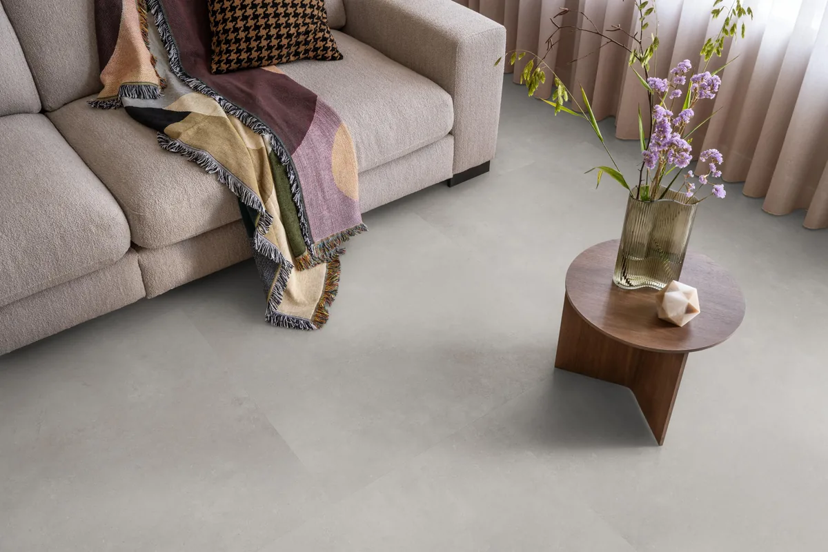 Southwark / Sarino grey, plak pvc in een woonkamer, met een beige bank en een ronde bijzettafel met bloemen