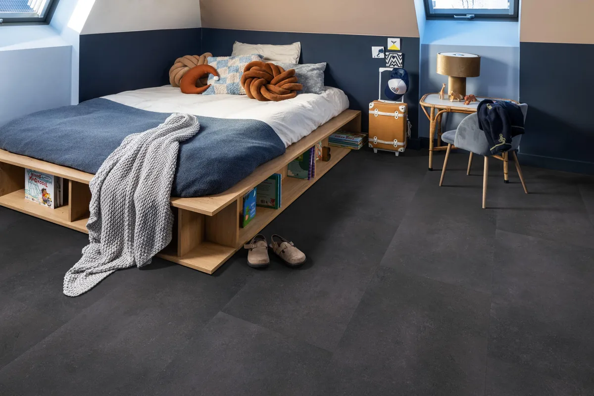 Southwark / Sarino anthracite, klik pvc in een slaapkamer onder een schuin dak, met een houten bedombouw en sloffen ervoor