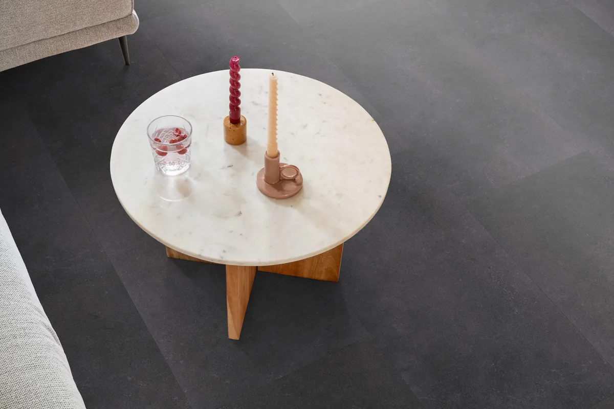 Southwark / Sarino anthracite, klik pvc in een woonkamer, met een ronde marmeren salontafel en twee kaarsen