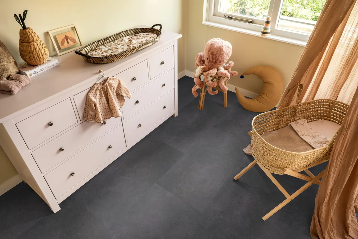 Southwark / Sarino anthracite, klik pvc in een babykamer, met een witte commode en een rieten wieg