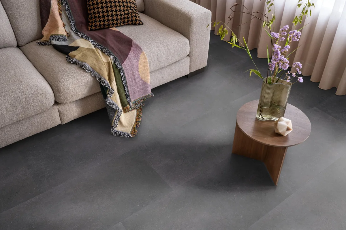 Southwark / Sarino anthracite, klik pvc in een woonkamer, met een beige bank en een ronde bijzettafel met bloemen