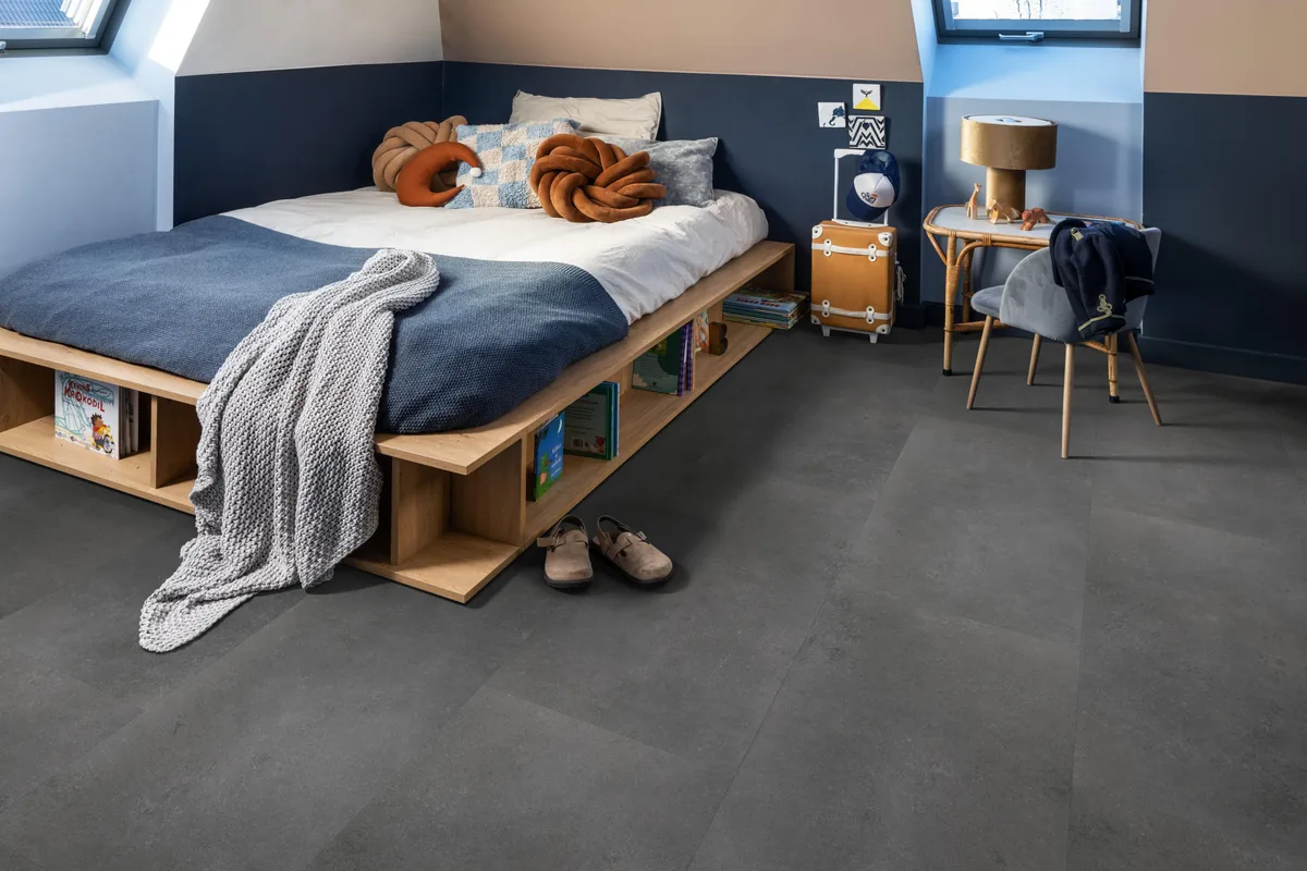 Southwark / Sarino dark grey, klik pvc in een slaapkamer onder een schuin dak, met een houten bedombouw en sloffen ervoor