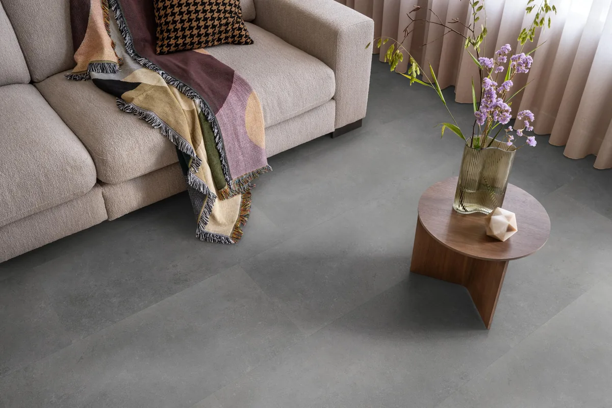 Southwark / Sarino dark grey, klik pvc in een woonkamer, met een beige bank en een ronde bijzettafel met bloemen