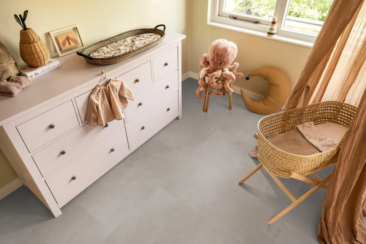 Southwark / Sarino light grey, klik pvc in een babykamer, met een witte commode en een rieten wieg