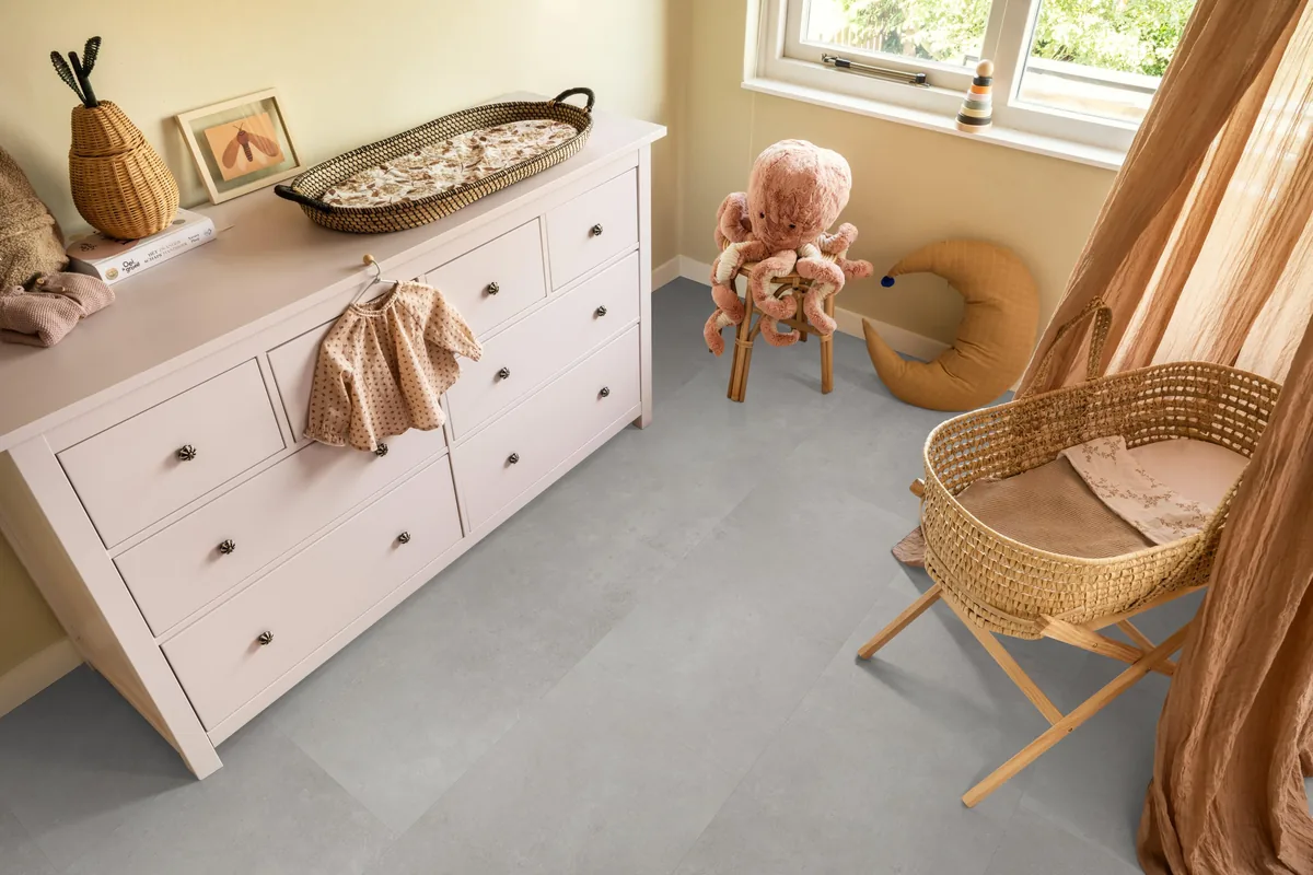 Southwark / Sarino grey, klik pvc in een babykamer, met een witte commode en een rieten wieg