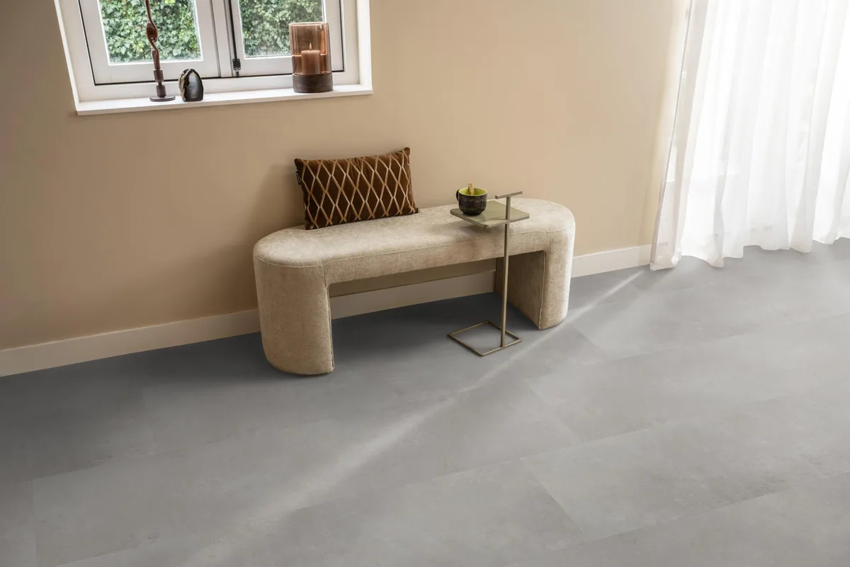 Southwark / Sarino grey, klik pvc in een hal, met een bankje onder het raam en zonlicht over de vloer