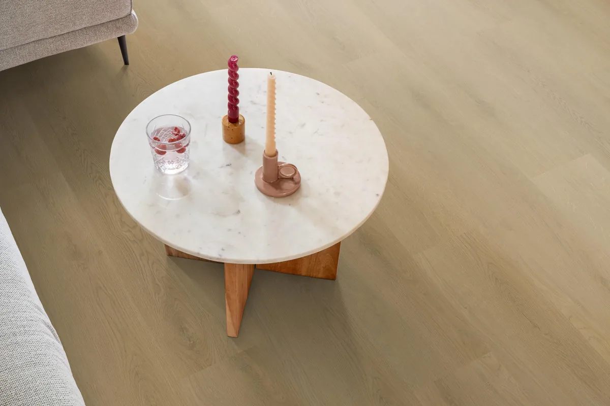 Merton / Navaro light oak, klik pvc in een woonkamer, met een ronde marmeren salontafel en twee kaarsen