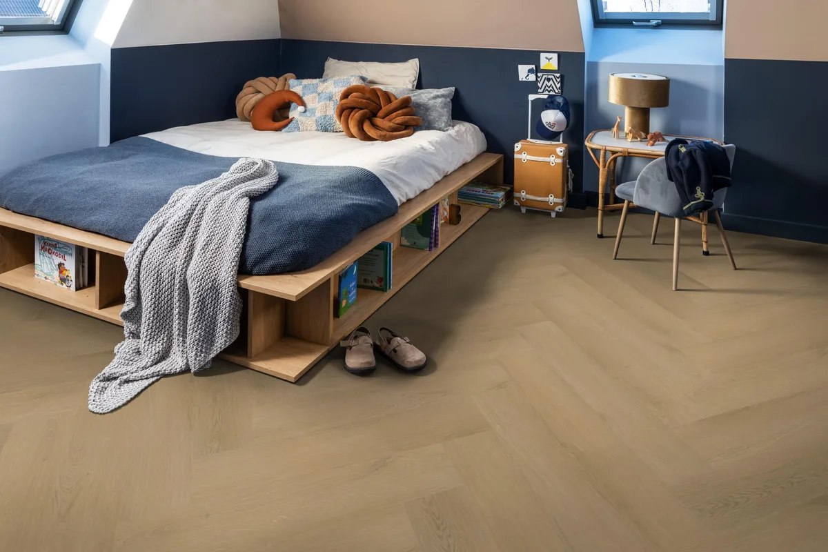 Merton / Navaro Light oak, visgraat klik pvc in een slaapkamer onder een schuin dak, met een houten bedombouw en sloffen ervoor