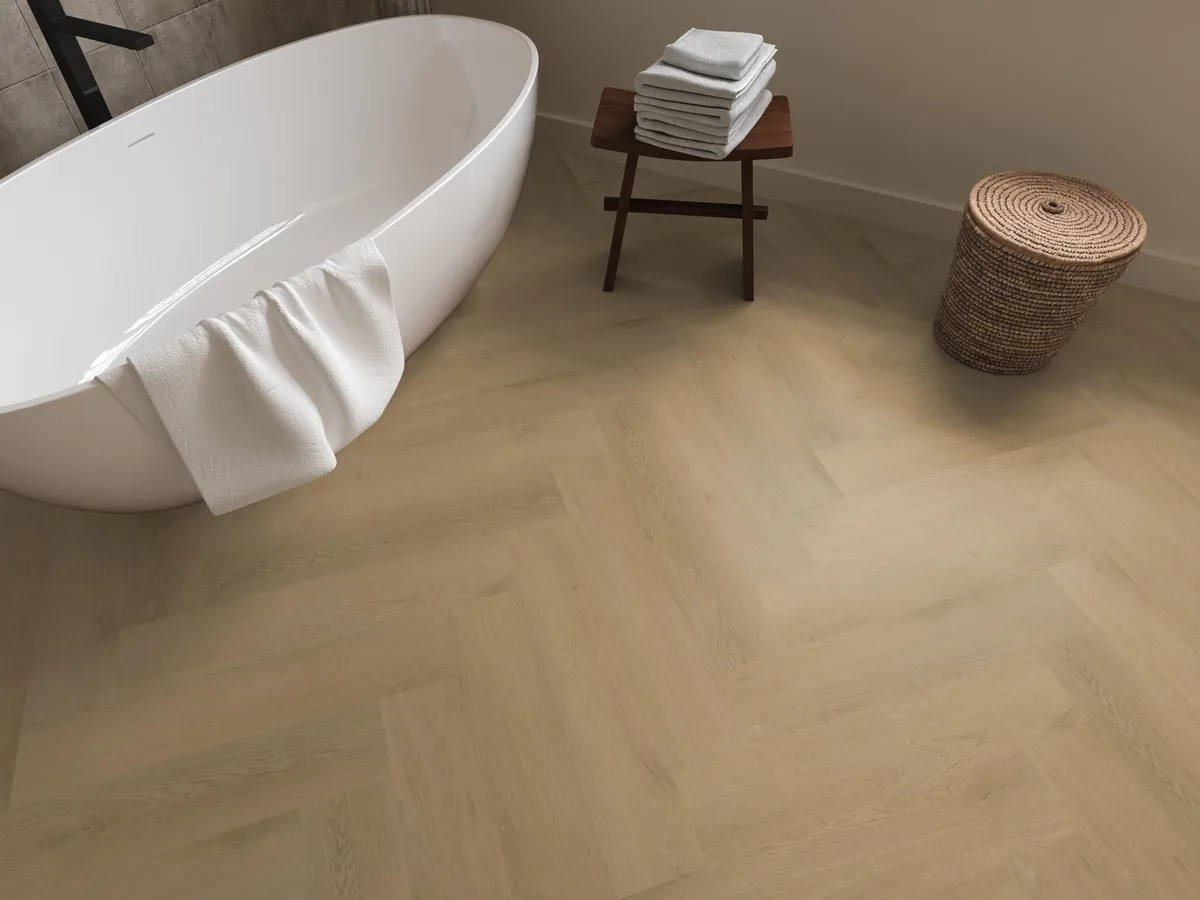 Merton / Navaro Light oak, visgraat klik pvc in een badkamer, met een vrijstaand bad en een rieten wasmand