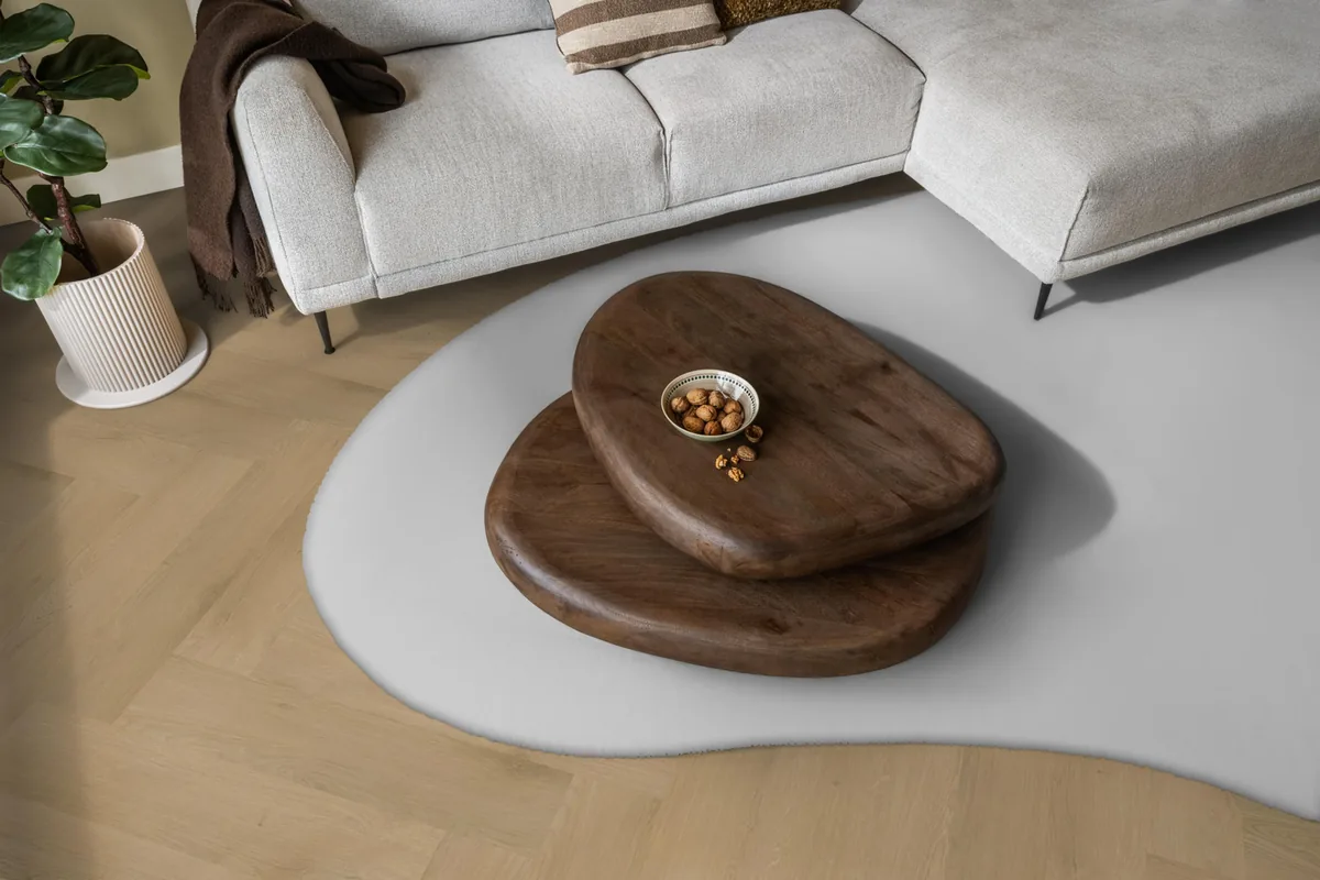 Merton / Navaro Light oak, visgraat klik pvc in een woonkamer, met een lichte hoekbank en een wit vloerkleed