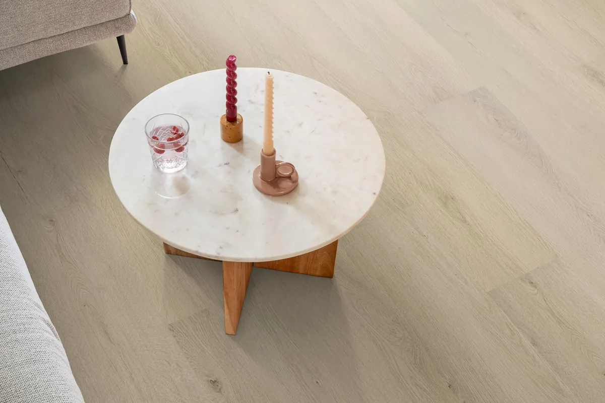 Mayfair / Marento warm oak, EVC-vloer in een woonkamer, met een ronde marmeren salontafel en twee kaarsen