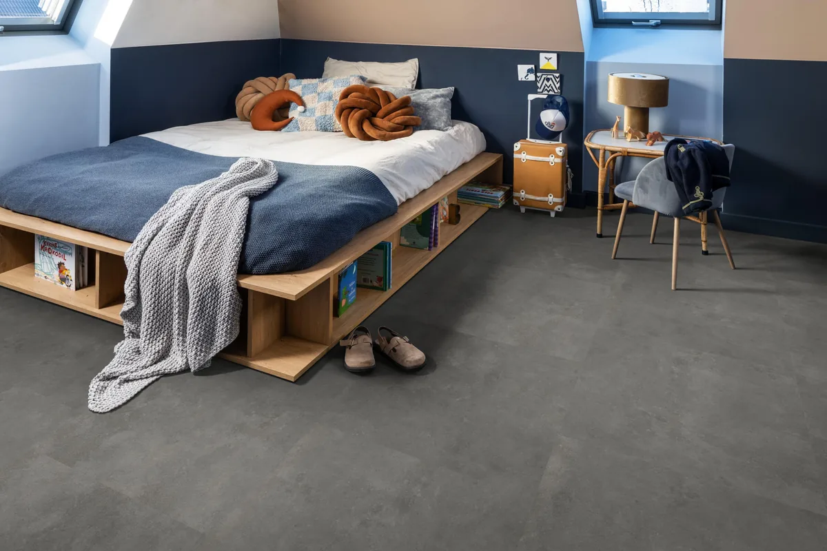 Victoria / Ceramo grey, klik pvc in een slaapkamer onder een schuin dak, met een houten bedombouw en sloffen ervoor