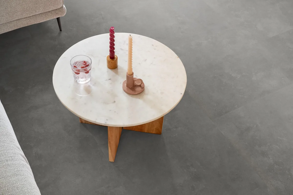 Victoria / Ceramo grey, klik pvc in een woonkamer, met een ronde marmeren salontafel en twee kaarsen