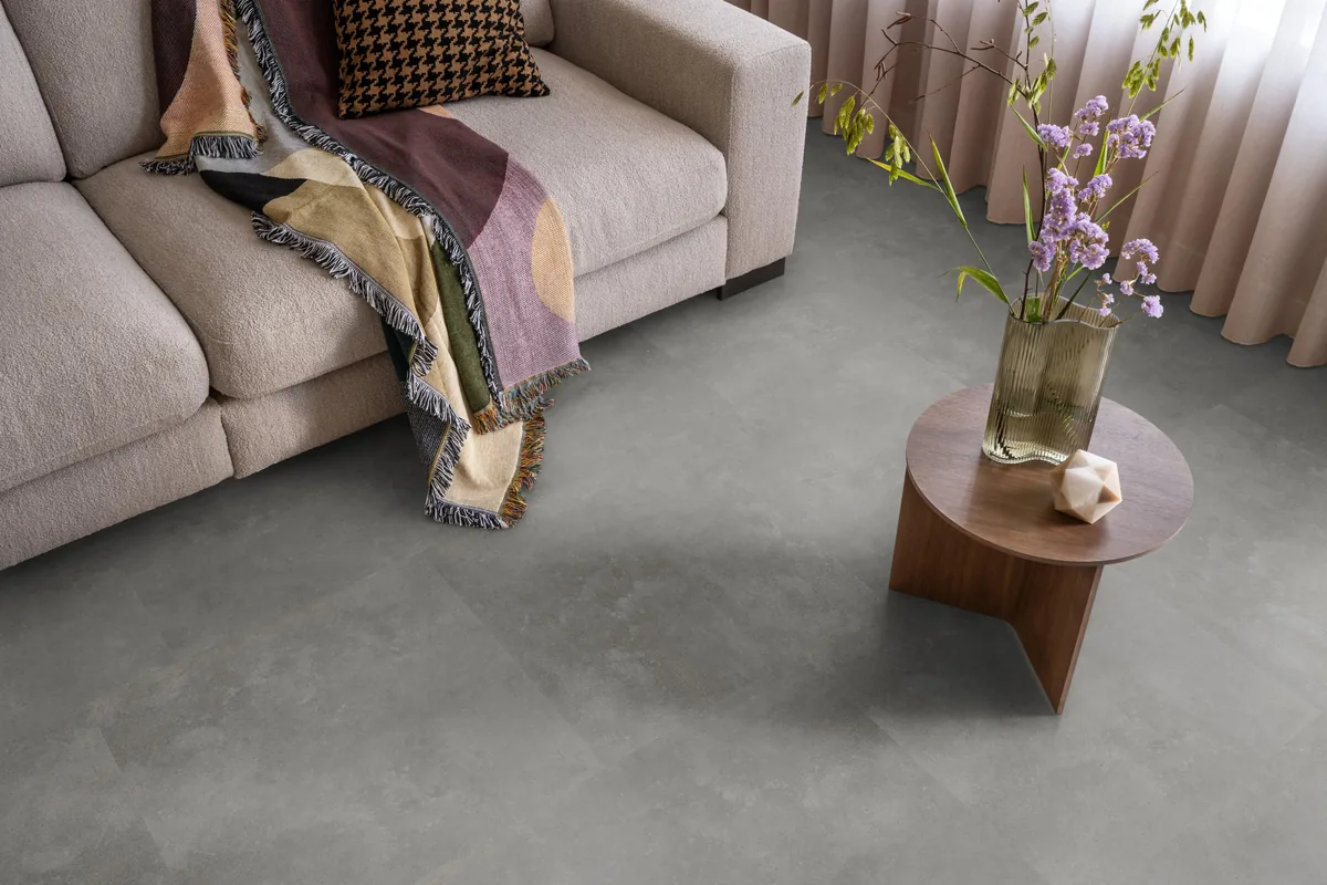Victoria / Ceramo grey, klik pvc in een woonkamer, met een beige bank en een ronde bijzettafel met bloemen