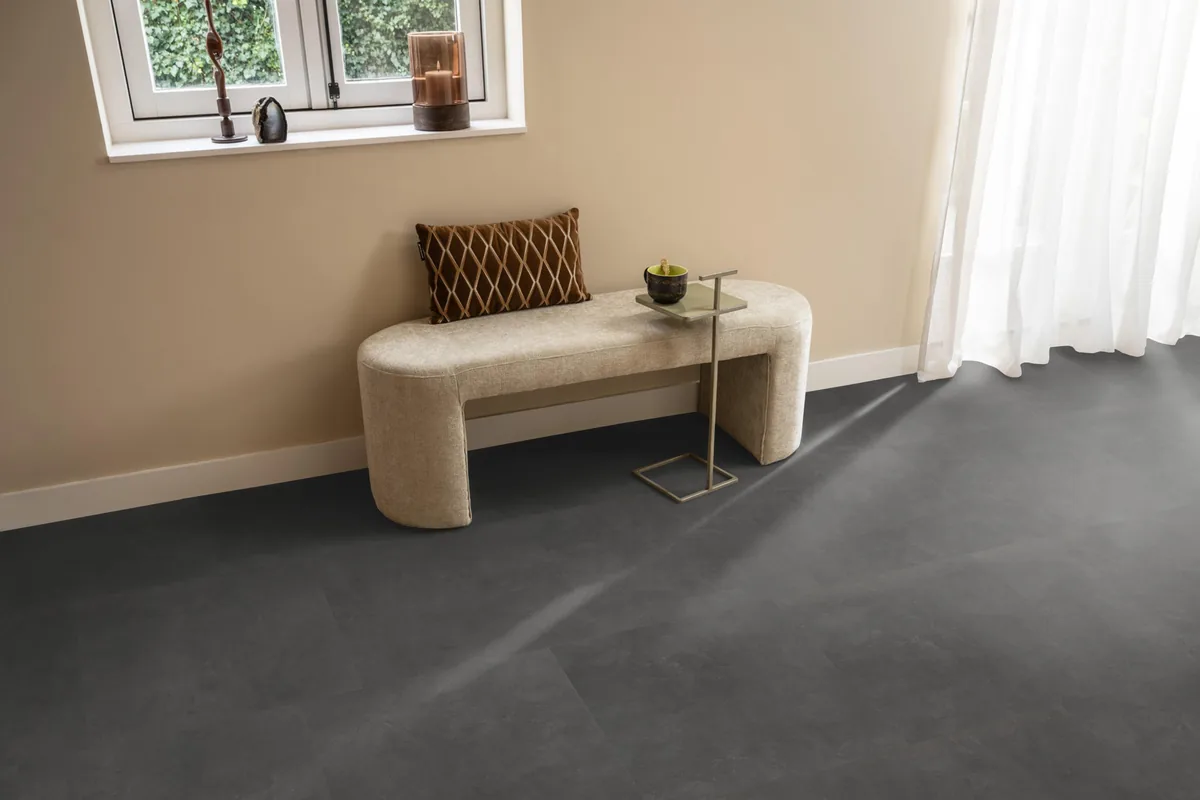 Victoria / Ceramo anthracite, klik pvc in een hal, met een bankje onder het raam en zonlicht over de vloer
