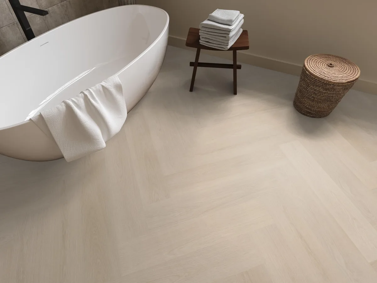 Brentford / Soleno Beige, visgraat klik pvc in een badkamer, met een vrijstaand bad en een rieten wasmand