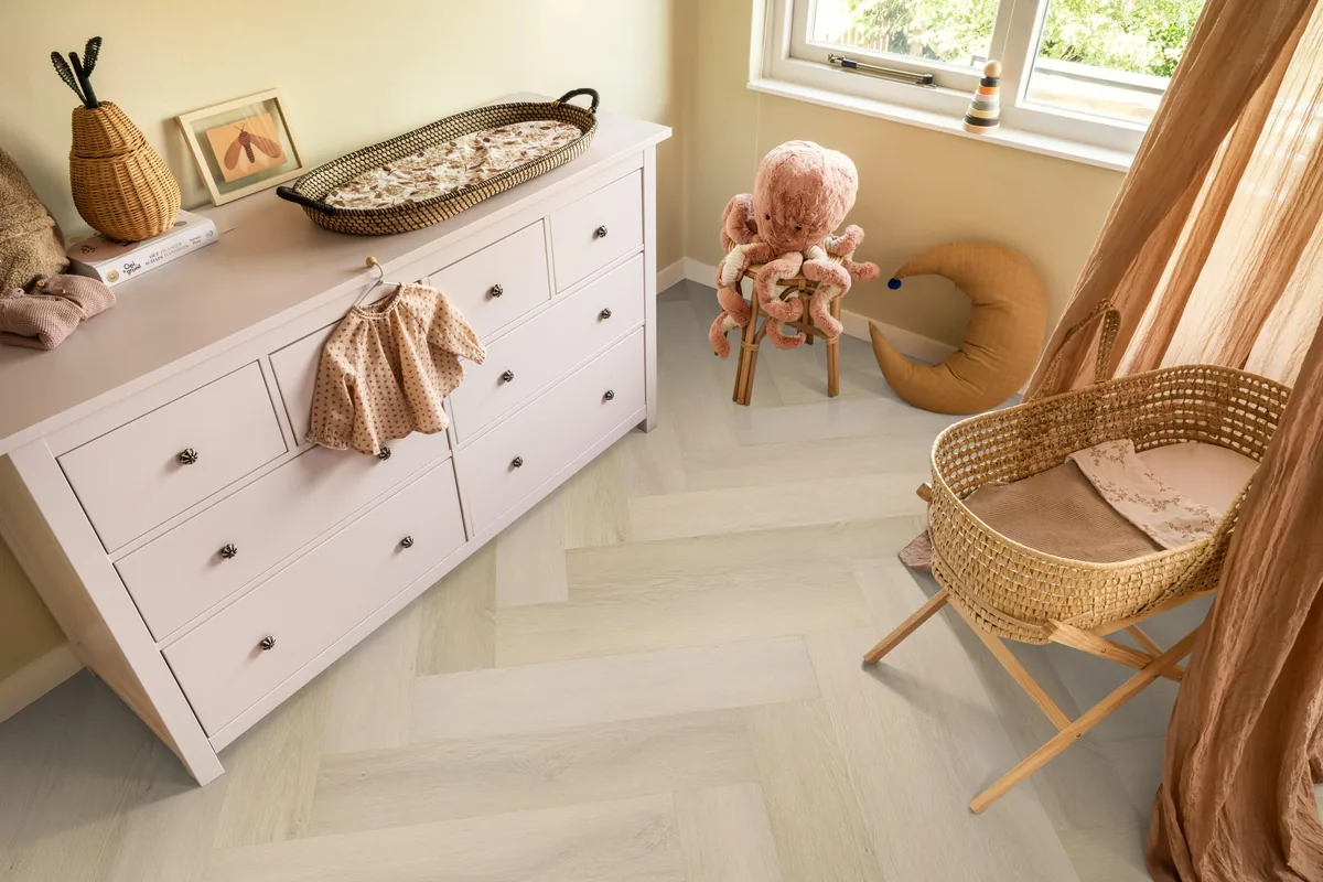Mayfair / Marento Natural, EVC-vloer in een babykamer, met een witte commode en een rieten wieg