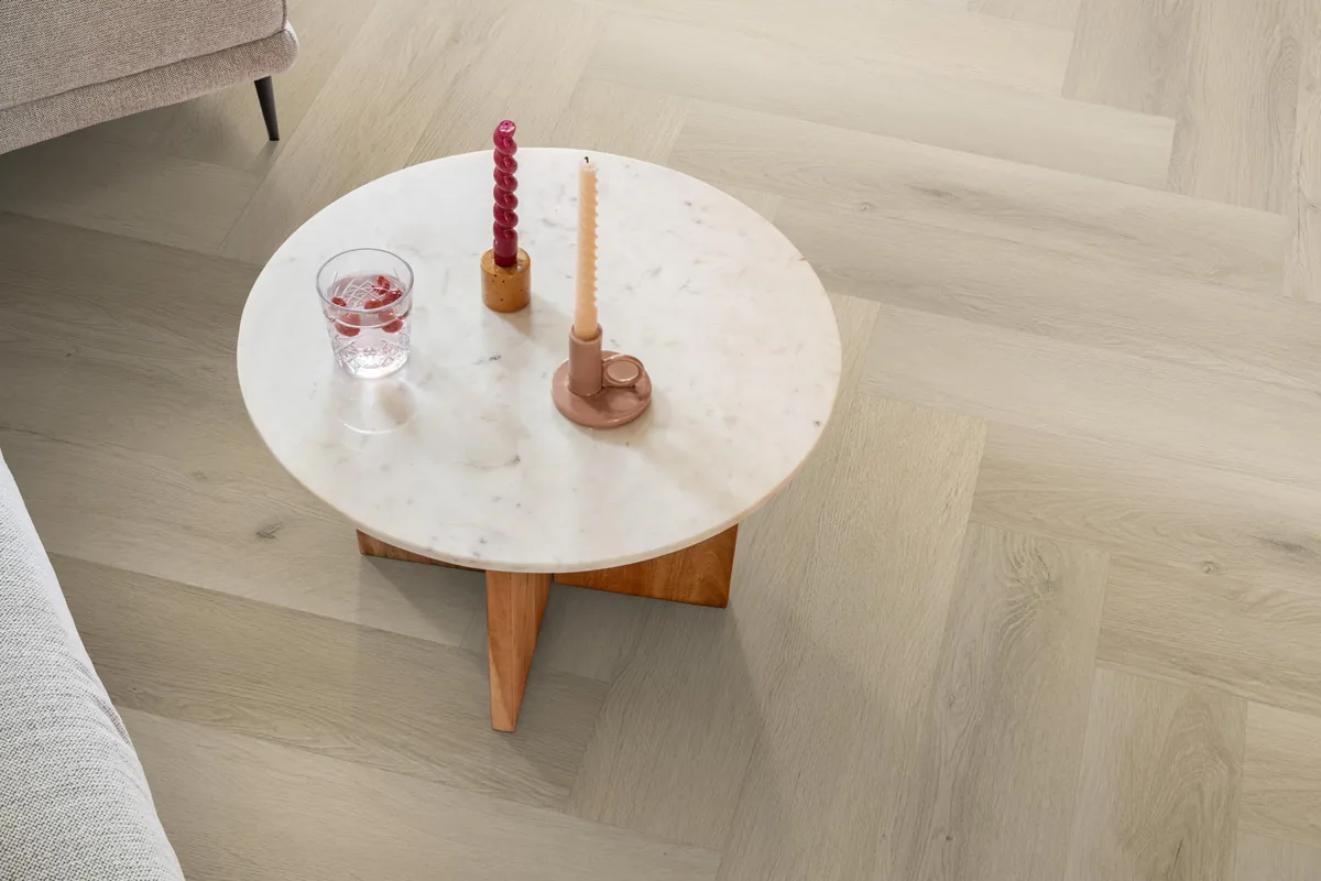 Mayfair / Marento Warm oak, EVC-vloer in een woonkamer, met een ronde marmeren salontafel en twee kaarsen