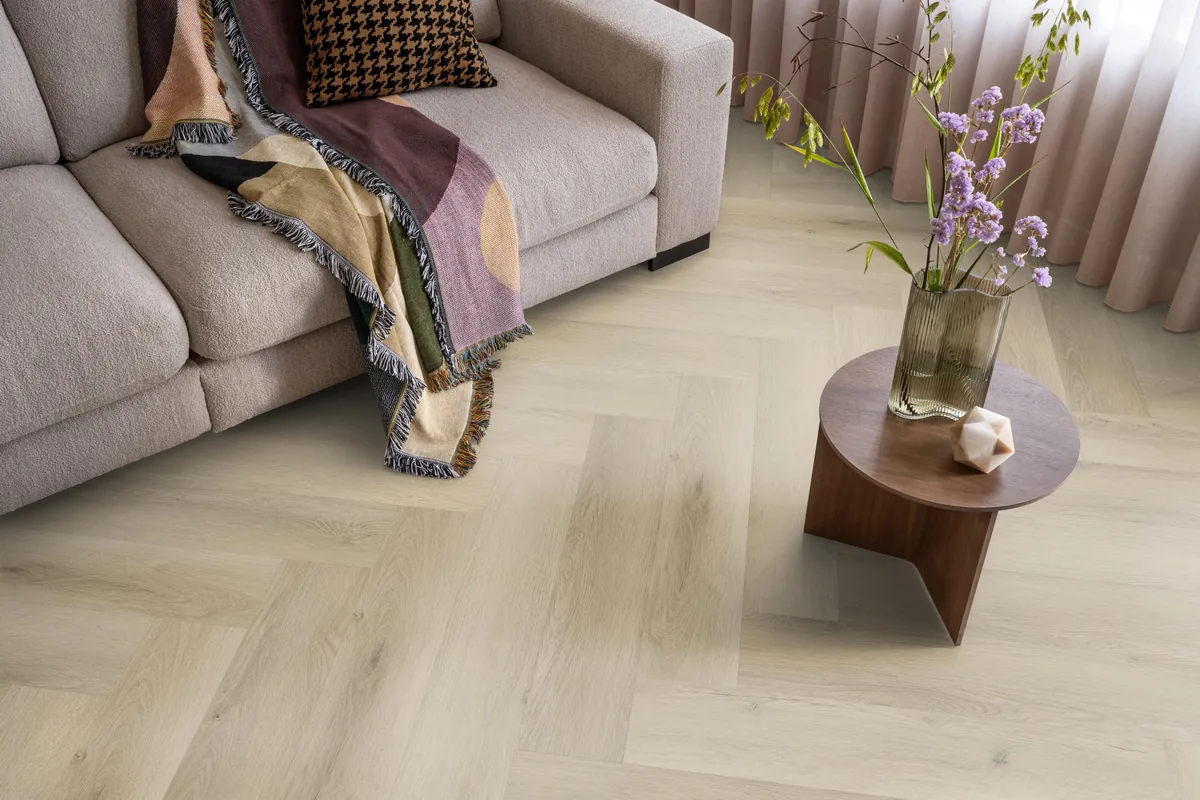 Mayfair / Marento Warm oak, EVC-vloer in een woonkamer, met een beige bank en een ronde bijzettafel met bloemen