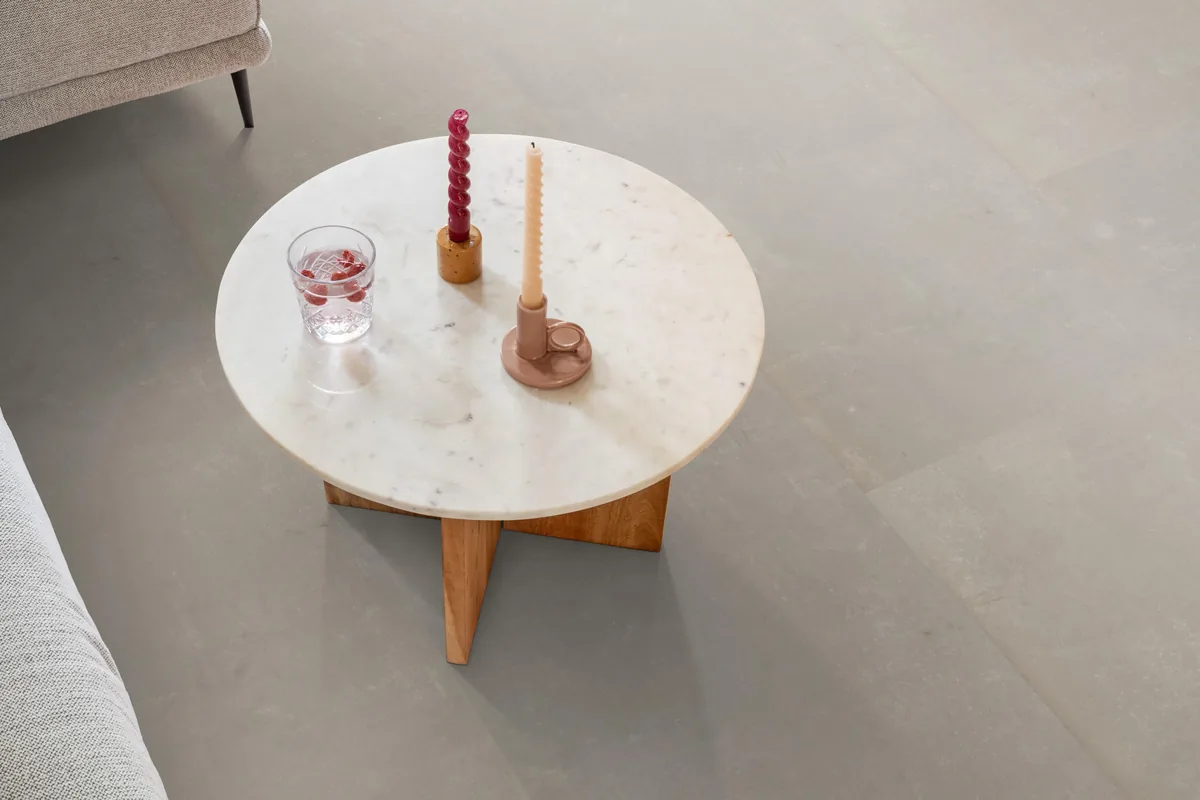 Westminster / Piero beige, klik pvc in een woonkamer, met een ronde marmeren salontafel en twee kaarsen