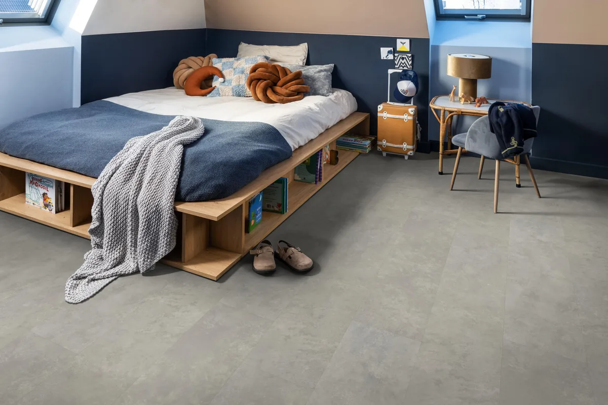 Finsbury / Viretto Light grey, plak pvc in een slaapkamer onder een schuin dak, met een houten bedombouw en sloffen ervoor