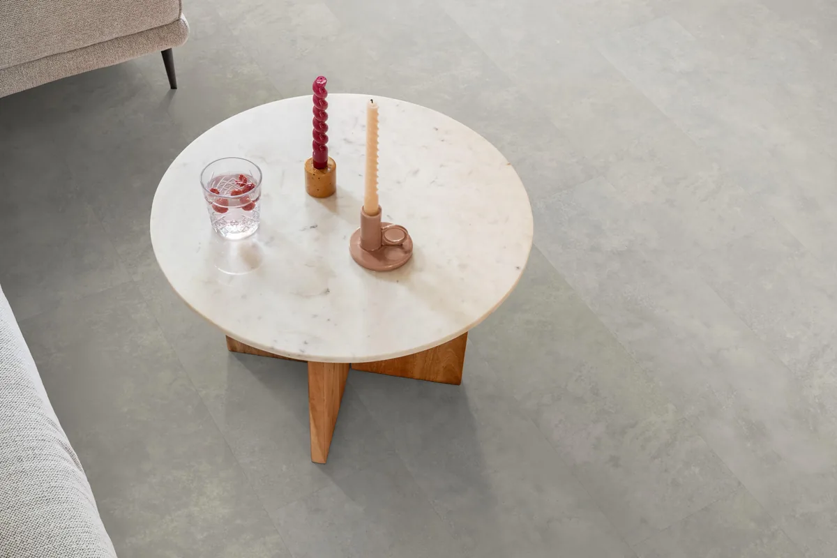Finsbury / Viretto Light grey, plak pvc in een woonkamer, met een ronde marmeren salontafel en twee kaarsen