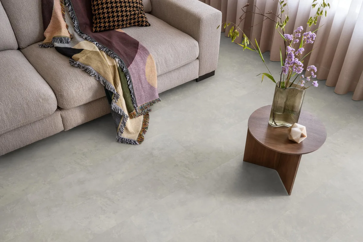 Finsbury / Viretto Light grey, plak pvc in een woonkamer, met een beige bank en een ronde bijzettafel met bloemen