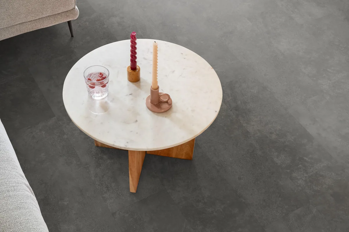 Finsbury / Viretto Grey, plak pvc in een woonkamer, met een ronde marmeren salontafel en twee kaarsen