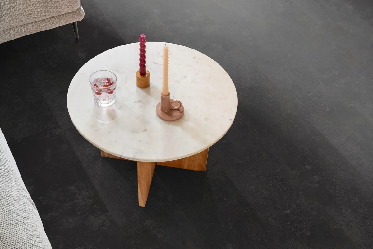 Finsbury / Viretto Anthracite, plak pvc in een woonkamer, met een ronde marmeren salontafel en twee kaarsen