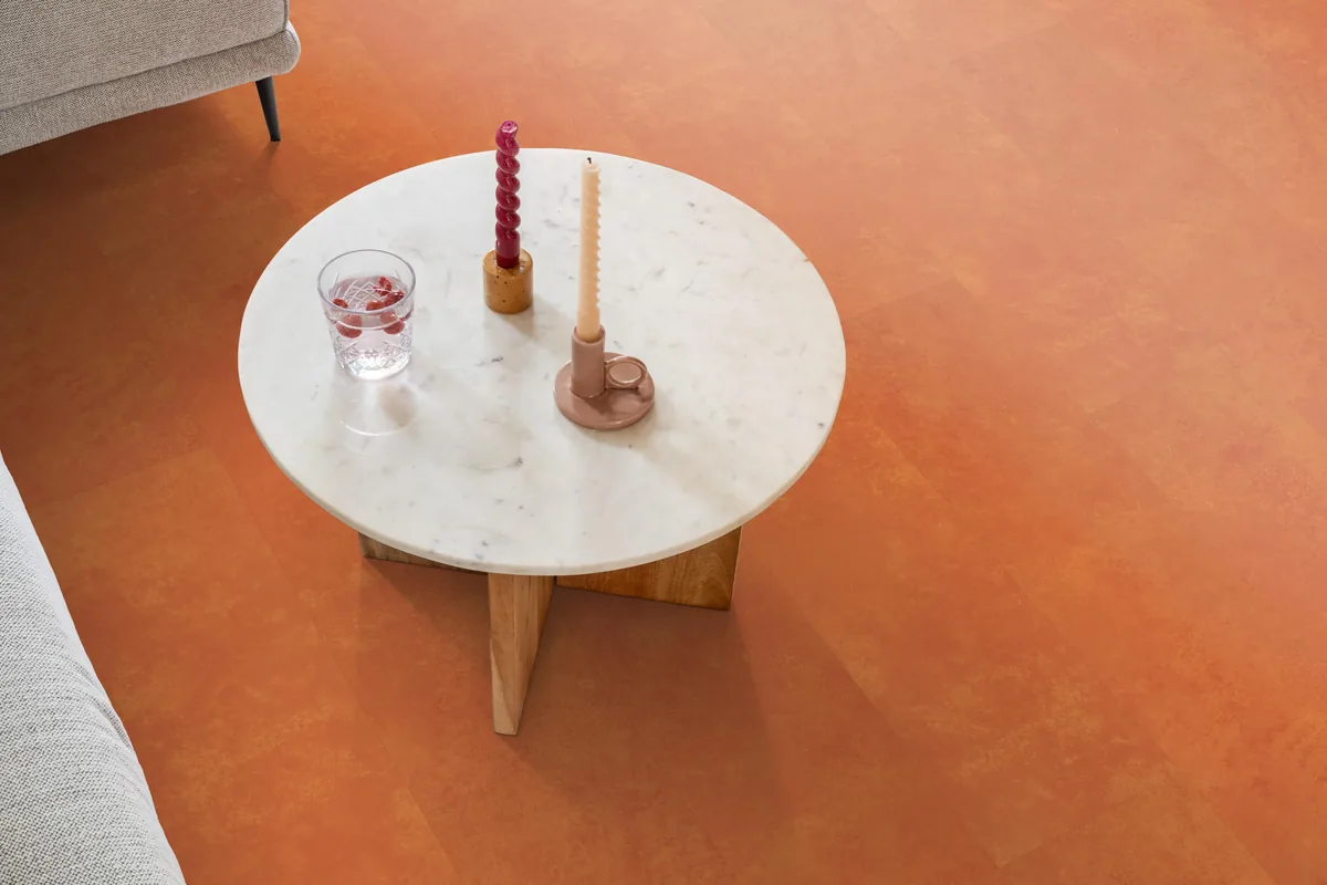 Finsbury / Viretto Orange, plak pvc in een woonkamer, met een ronde marmeren salontafel en twee kaarsen