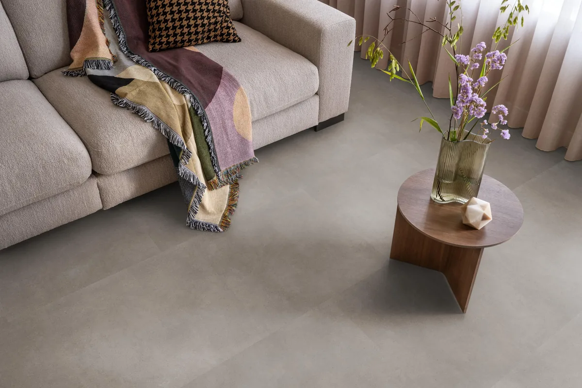 Peckham / Baroso taupe, klik pvc in een woonkamer, met een beige bank en een ronde bijzettafel met bloemen