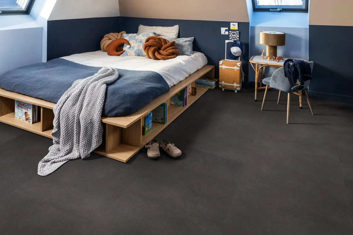 Peckham / Baroso anthracite, klik pvc in een slaapkamer onder een schuin dak, met een houten bedombouw en sloffen ervoor