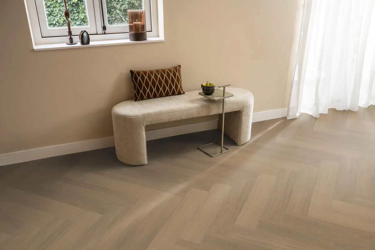 Sutton / Viranto warm natural, visgraat plak pvc in een hal, met een bankje onder het raam en zonlicht over de vloer