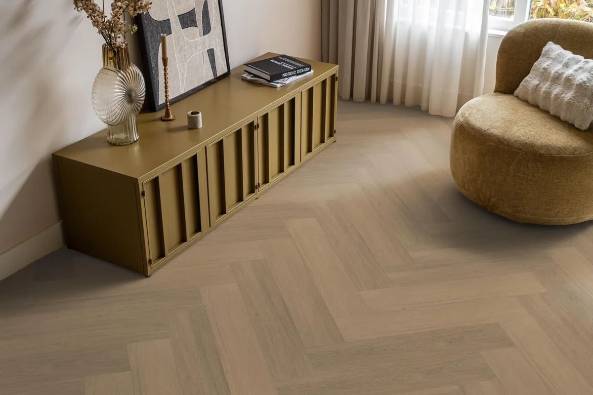 Sutton / Viranto warm natural, visgraat plak pvc in een woonkamer, met een okergeel dressoir en een ronde fauteuil