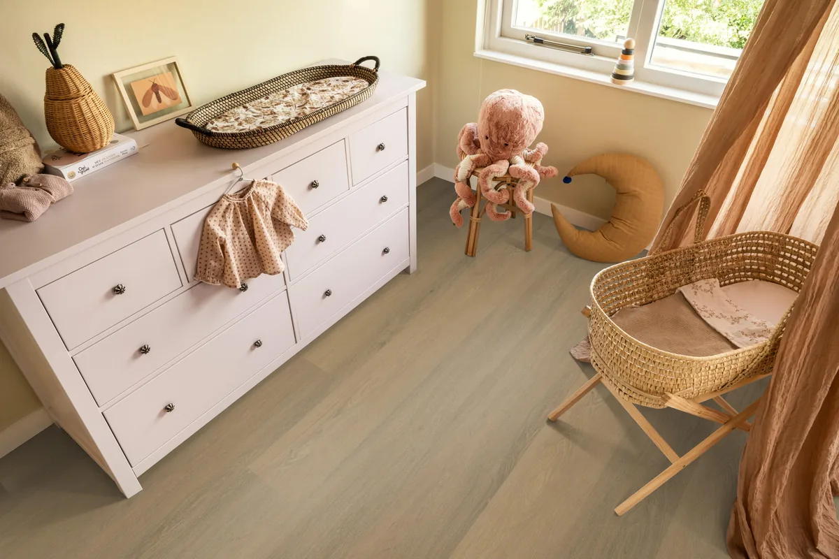 Sutton / Viranto Warm natural, klik pvc in een babykamer, met een witte commode en een rieten wieg