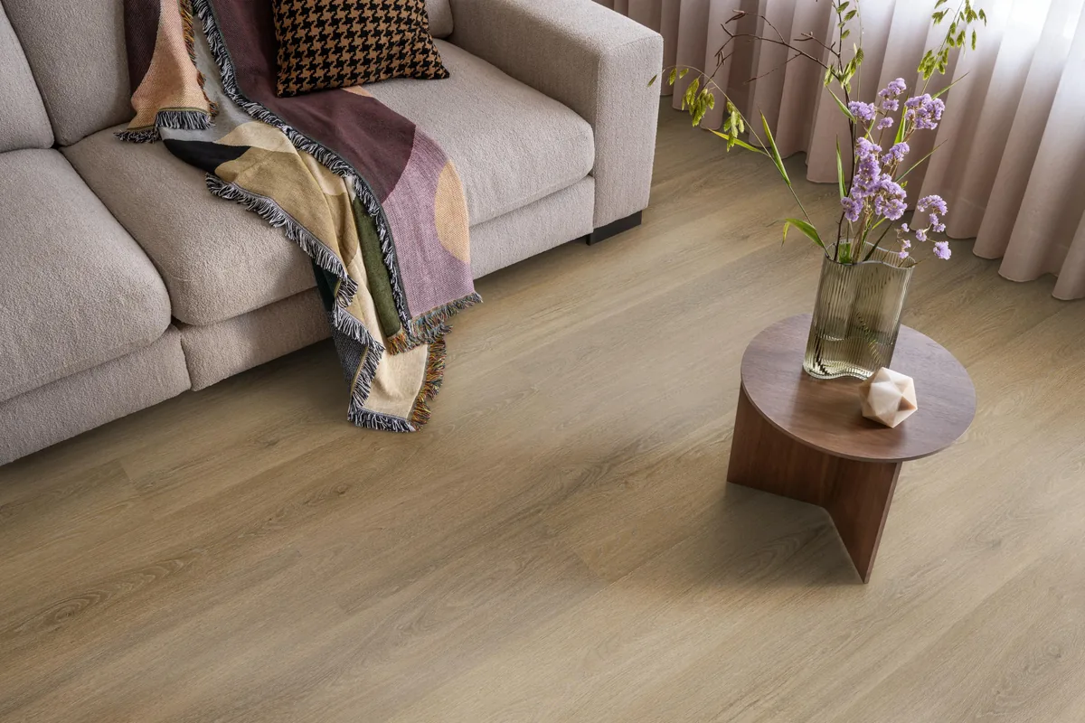 Sutton / Viranto Light brown, klik pvc in een woonkamer, met een beige bank en een ronde bijzettafel met bloemen