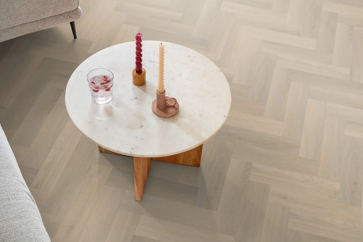 YUP / Spigato small beige, visgraat plak pvc in een woonkamer, met een ronde marmeren salontafel en twee kaarsen