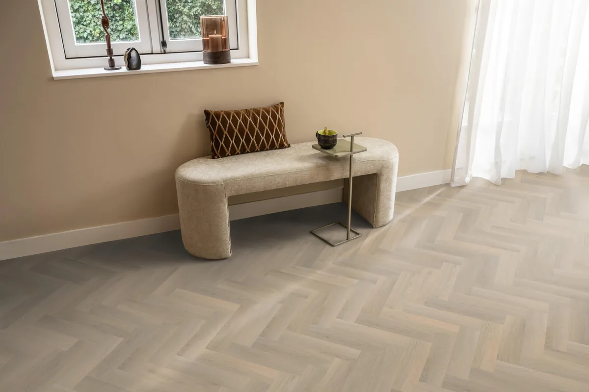 YUP / Spigato small beige, visgraat plak pvc in een hal, met een bankje onder het raam en zonlicht over de vloer