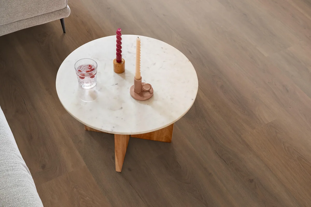 Parramatta / Robusto warm brown, plak pvc in een woonkamer, met een ronde marmeren salontafel en twee kaarsen