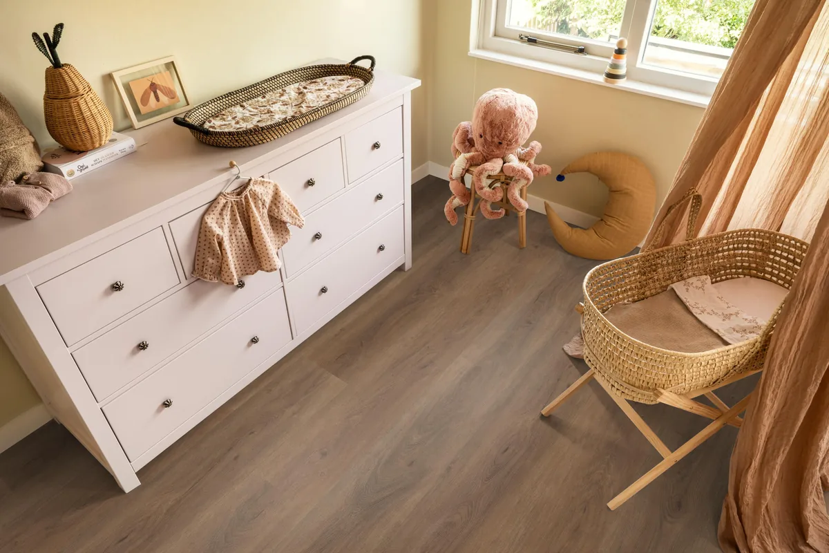 Parramatta / Robusto warm brown, plak pvc in een babykamer, met een witte commode en een rieten wieg